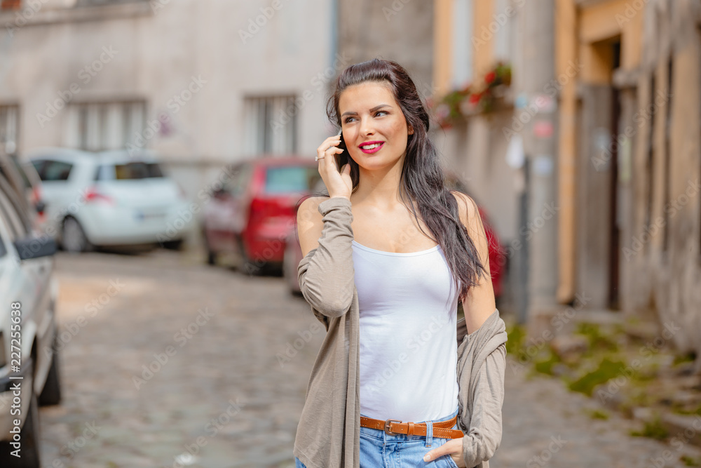 Cute young woman using cellphone in urban surroundings.
