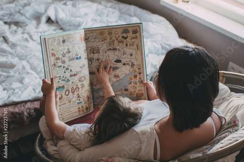 Mother and daughter watching a book, family portrait