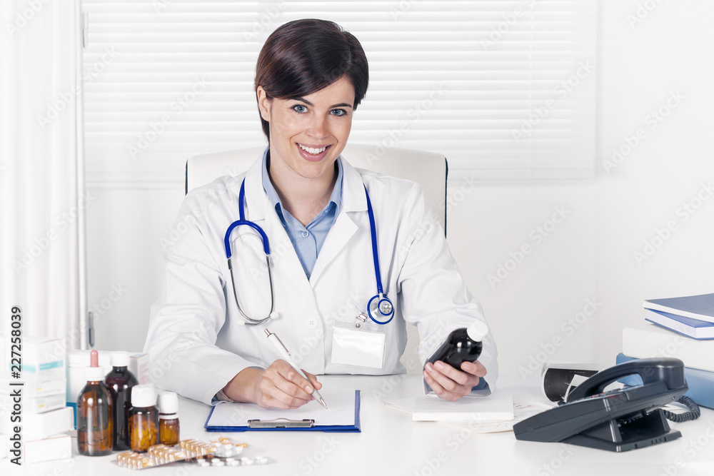 Smiling young doctor writing out a prescription Smiling young doctor writing out a prescription