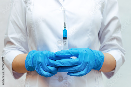 Syringe with a blue medical drug in the doctor hands dressed in the medical gown.