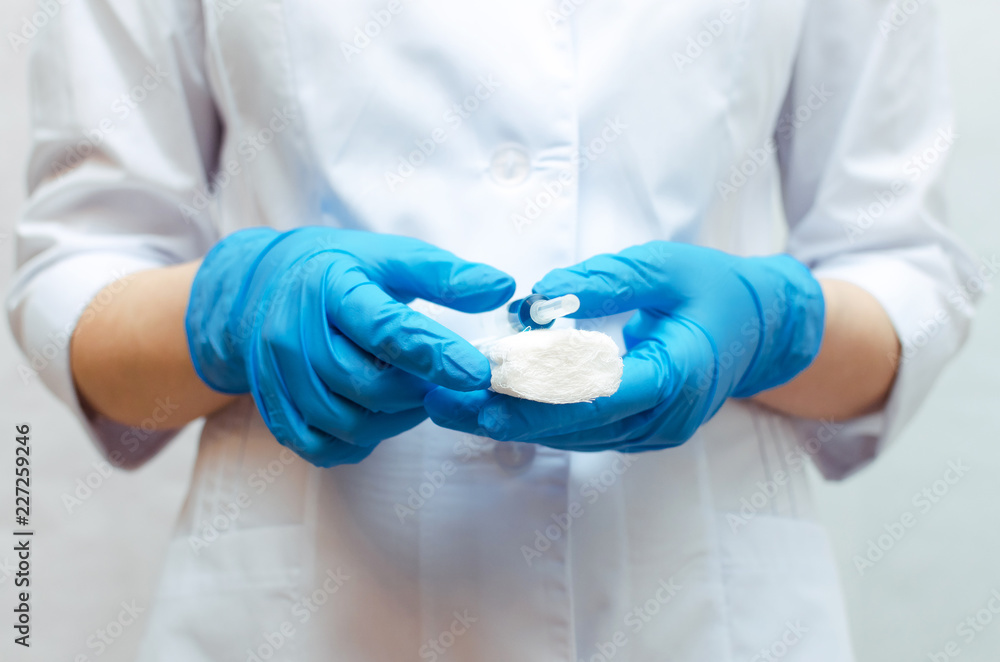 Syringe with a blue medical drug and a bandage in the doctor hands dressed in the medical gown. Syringe with a blue medical drug and a bandage in the doctor hands dressed in the medical gown.