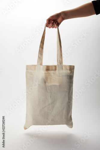 cropped image of woman holding cotton bag with food delivery on white