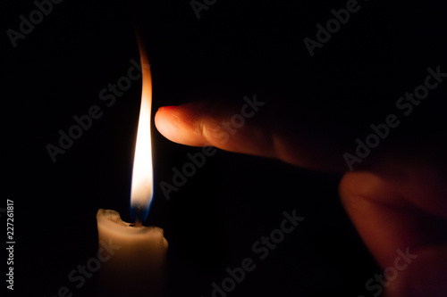 A person takes his finger very close to candle flame