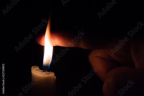 A person takes his finer into the candle flame. Burning in flames