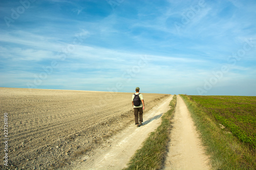 Man traveler walking along a dirt road