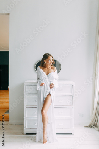 Conceptual wedding  the morning of the bride in the European style. Boudoir dress and a bouquet of flowers  fees in the interior Studio. White minimalism for the bride