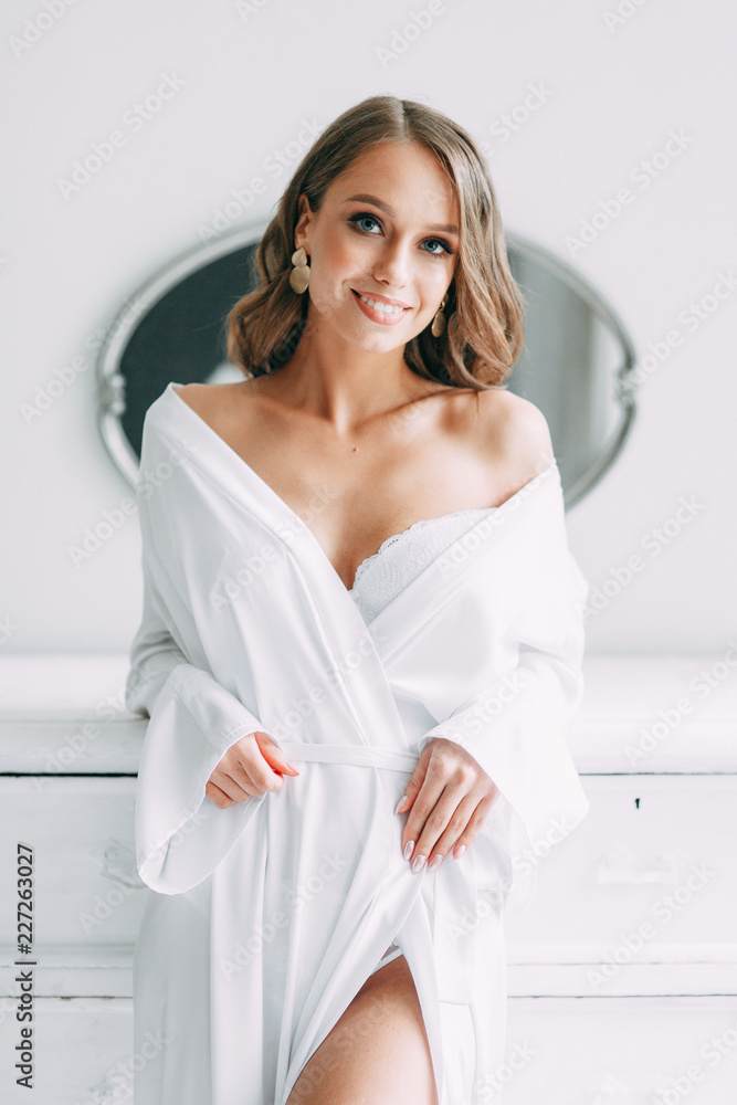 Conceptual wedding, the morning of the bride in the European style. Boudoir dress and a bouquet of flowers, fees in the interior Studio. White minimalism for the bride