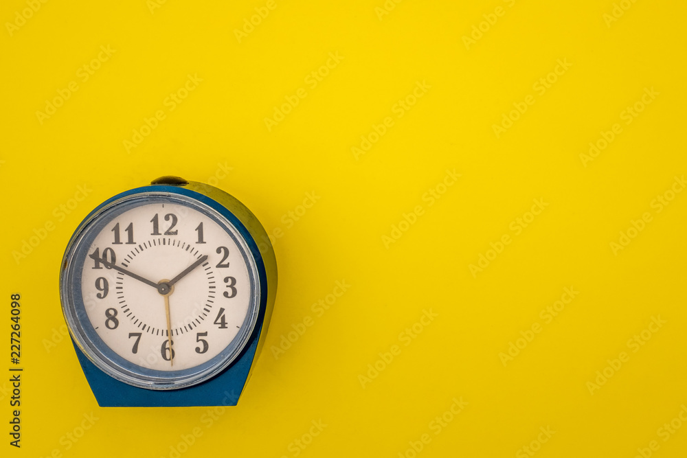 An old alarm clock on a yellow background. An old alarm clock on a yellow background.
