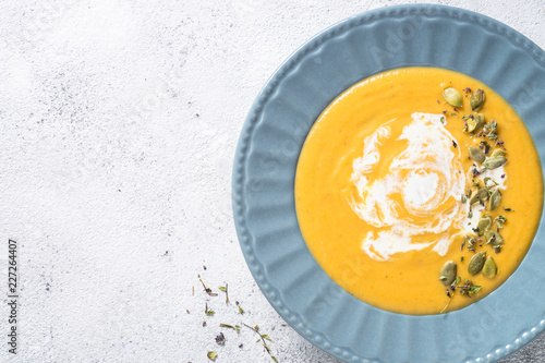 Pumpkin cream soup on light stone table.
