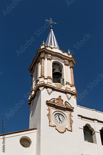 Campanario en torre de iglesia con reloj en fachada.