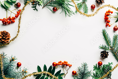 Flat lay with festive arrangement of pine tree branches, common sea buckthorn and Christmas decorations on white tabletop