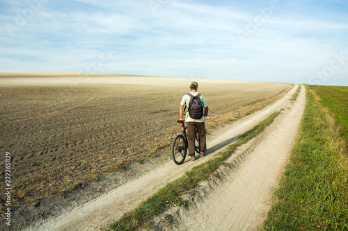 Man traveler walking with a bike through a country road