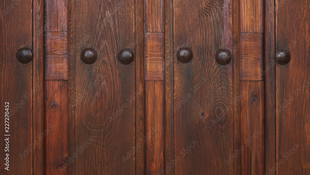 Cropped, ornate cherry-brown wooden door with metal studs, a medieval, rustic or antique design. Ornamental background concept for home ownership, status, privacy or interior design with copy space Cropped, ornate cherry-brown wooden door with metal studs, a medieval, rustic or antique design. Ornamental background concept for home ownership, status, privacy or interior design with copy space