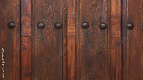 Cropped, ornate cherry-brown wooden door with metal studs, a medieval, rustic or antique design. Ornamental background concept for home ownership, status, privacy or interior design with copy space