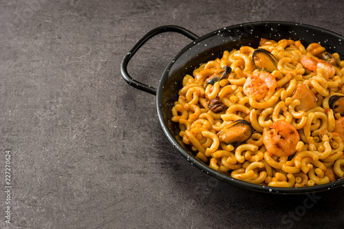 Traditional Spanish fideua. Noodle paella on black stone. Copyspace