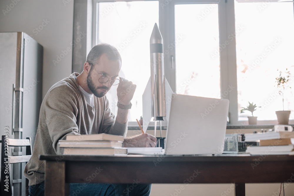 handsome engineer modeling rocket and looking at laptop at home handsome engineer modeling rocket and looking at laptop at home