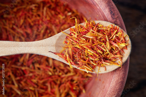 Safflower petals (Saffron substitute) in wooden spoon. Top view
