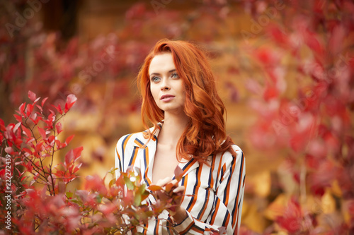 Outdoors portrait of beautiful woman with red hair and smoky eyes makeup photo