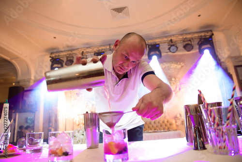 Barman adding cocktail ingredients on whiskey cocktails on bar counter