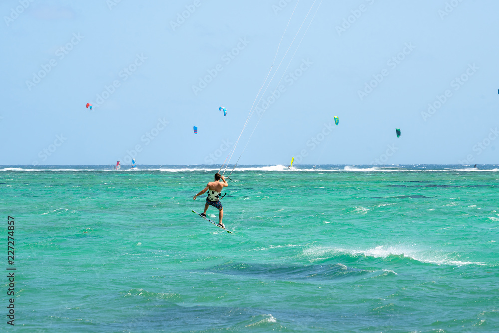 Kitesurfing kitesurfer near Mauritius beach and sea, waves in the water. Beautiful sea water Indian Ocean. Travel to Mauritius island a paradise island in Africa. Kite surfing.