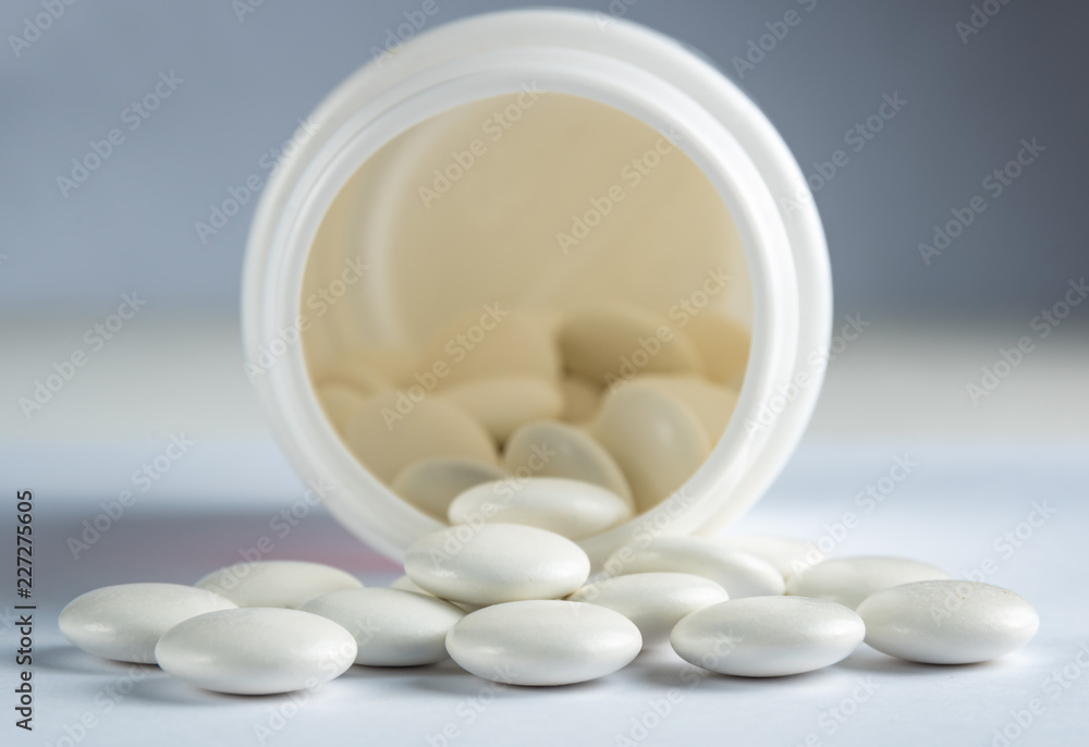 White round tablets covered with a cover are scattered from a plastic can with themWhite round tablets covered with a cover are scattered from a plastic can with them White round tablets covered with a cover are scattered from a plastic can with themWhite round tablets covered with a cover are scattered from a plastic can with them