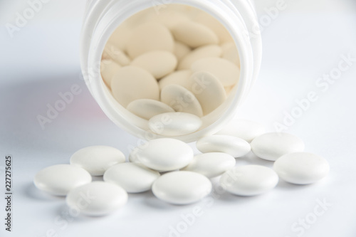White round tablets covered with a cover are scattered from a plastic can with themWhite round tablets covered with a cover are scattered from a plastic can with them