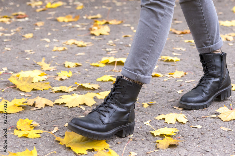 Legs of a girl in boots, yellow leaves, the theme of autumn