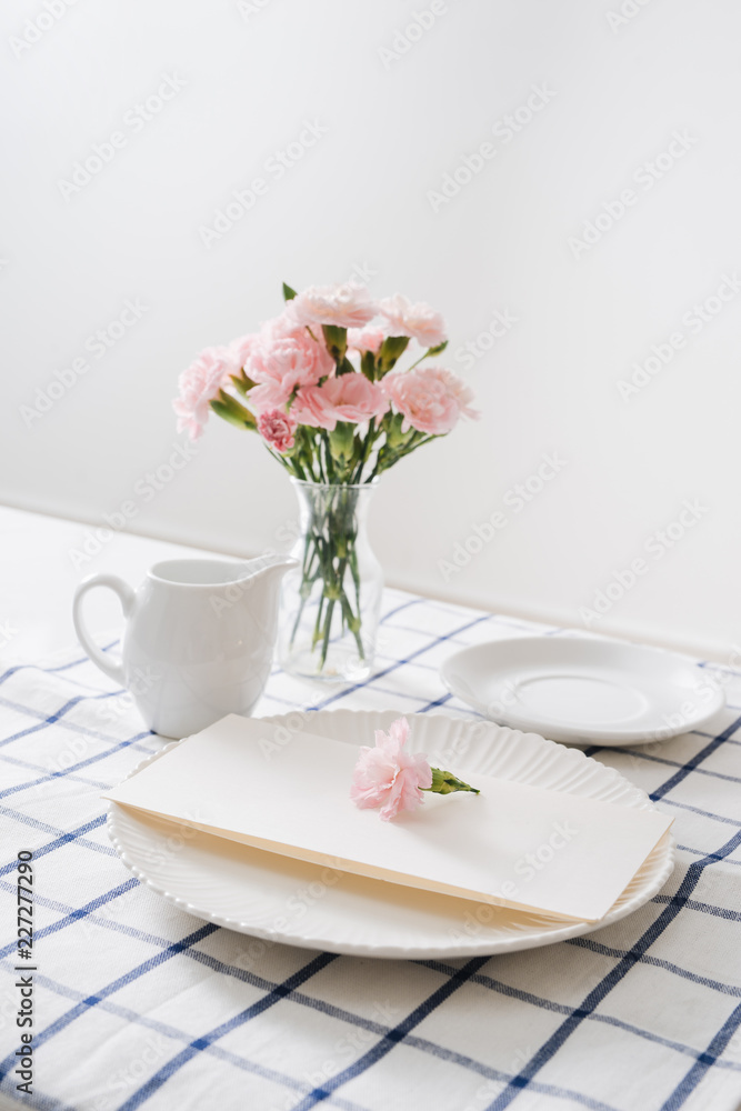 Table setting with dishes, cutlery and flowers on white background Table setting with dishes, cutlery and flowers on white background