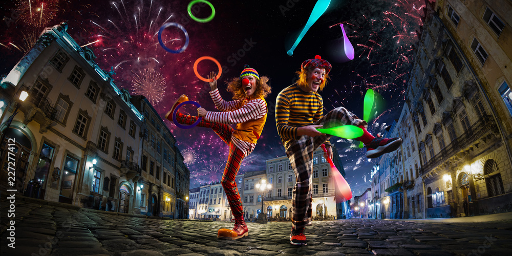 Night street circus performance whit two clowns, juggler. Festival city background. fireworks and Celebration atmosphere. - obrazy, fototapety, plakaty 