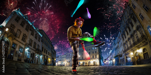 Night street circus performance whit clown, juggler. Festival city background. fireworks and Celebration atmosphere. © Anna Stakhiv