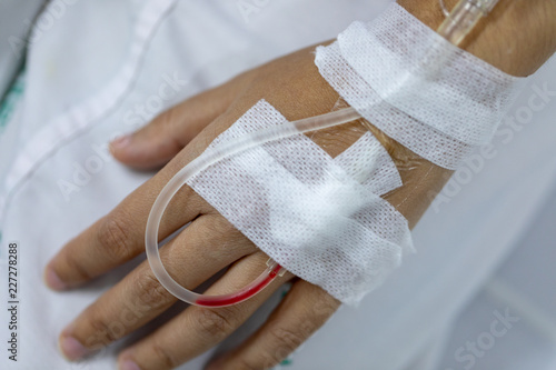 Close up hand woman patient with injection Saline in hand and during lying rehabilitation beds the hospital.