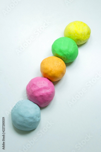 Close up of homemade colorful playdough on a white table.