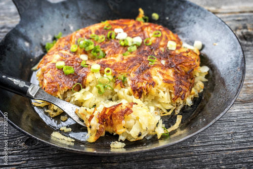 Traditional Swiss Rösti as side dish with leek as closeup in a frying pan
