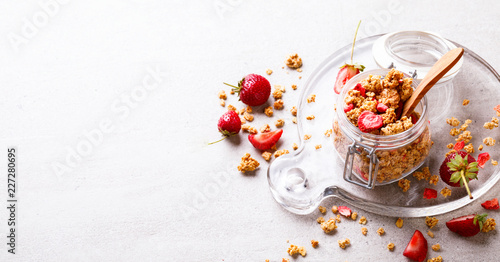 Granola Cereal bar with Strawberries on the Gray Background in a glass jar. Muesli Breakfast. Healthy Food sweet dessert snack. Diet Nutrition Concept. Vegetarian food.Copy space