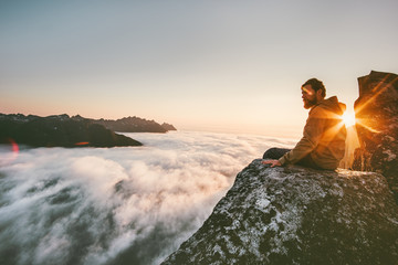 Man relaxing alone on the edge cliff  mountain above clouds travel adventure lifestyle harmony with nature vacations in Norway