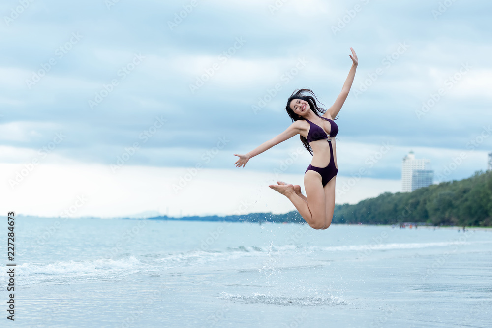 Summer holiday vacation concept. Traveler woman lifestyle in bikini jumping and enjoying relaxing on destinations sea beach..