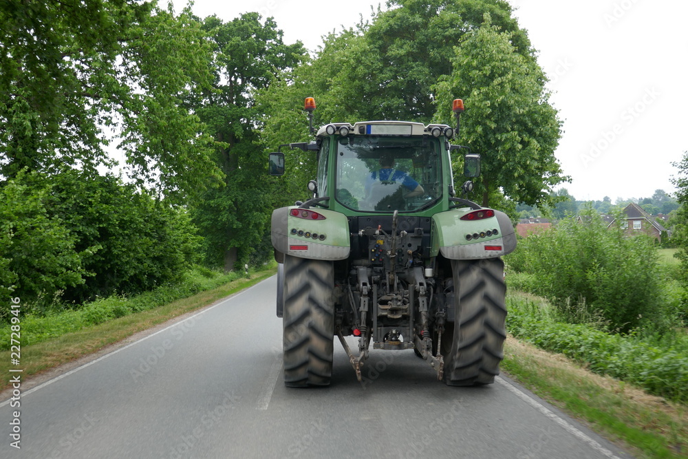 Obraz premium Tractor from behind, on a lonely country road