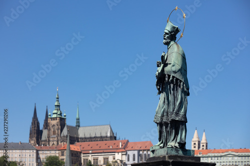 Statue des heiligen Nepomuk auf der Karlsbrücke in Prag mit Veitsdom im Hintergrund