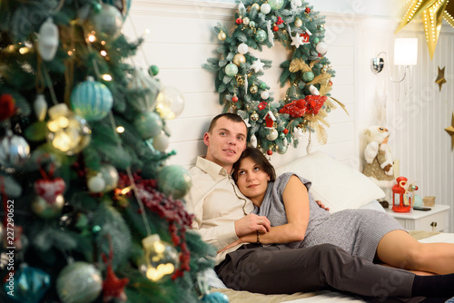 Pregnant mother and her husband at home with christmas decorations © nagaets