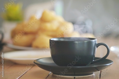 Hot coffee in ceramic black glass serve on wooden table in front of the chainess donut in the morning. photo