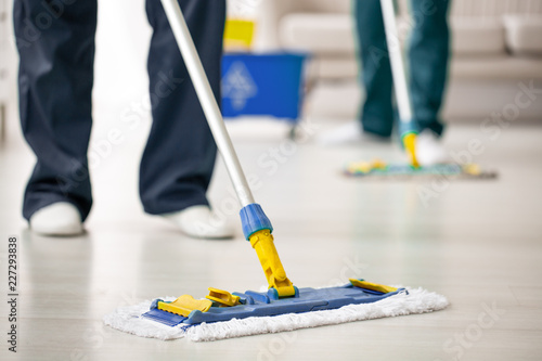 Fotografía Close-up on mop on the floor holding by cleaning expert while purifying interior