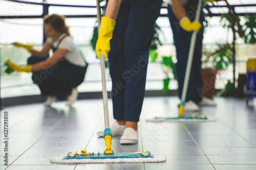 Close-up on professional cleaner with yellow gloves and mop wiping the floor photo