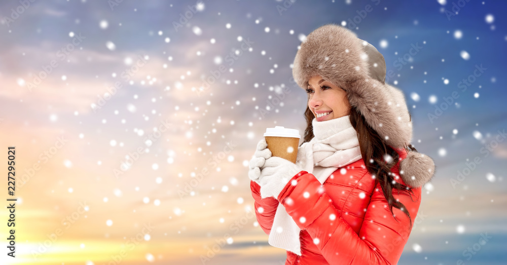 people, hot drinks and winter concept - happy woman in fur hat with coffee cup hat over snow and sky background people, hot drinks and winter concept - happy woman in fur hat with coffee cup hat over snow and sky background