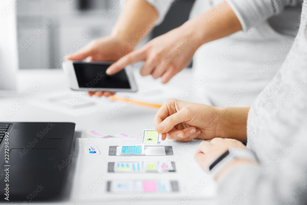 app design, technology and business concept - web designers or developers with smartphone working on user interface at office app design, technology and business concept - web designers or developers with smartphone working on user interface at office