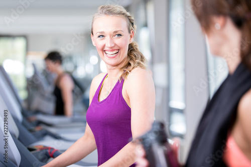 junge, hübsche Frau trainiert im Fitnessstudio auf dem Laufband laufen.