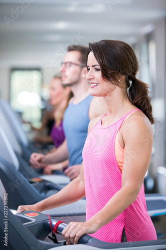 junge, hübsche Frau trainiert im Fitnessstudio auf dem Laufband laufen.