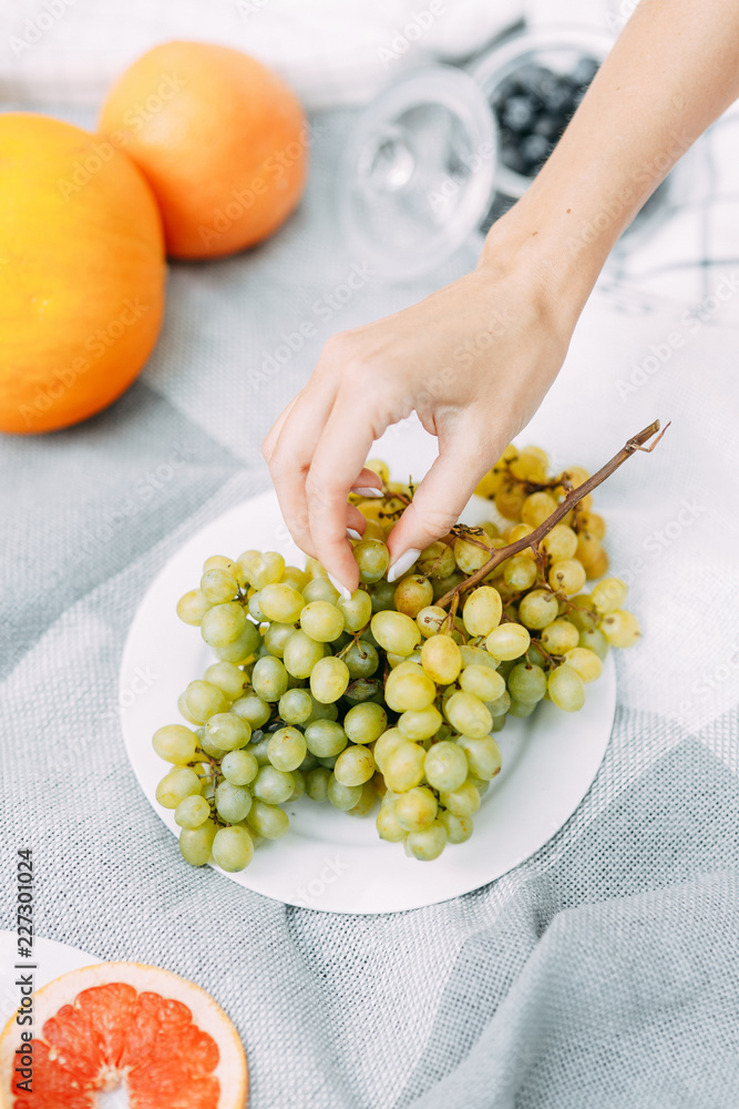 Fototapeta premium Summer picnic in nature, beautiful fruits and wine. Pomegranate, apples, pastries and bread on a blanket. Cheese and cherries in a beautiful design on the table