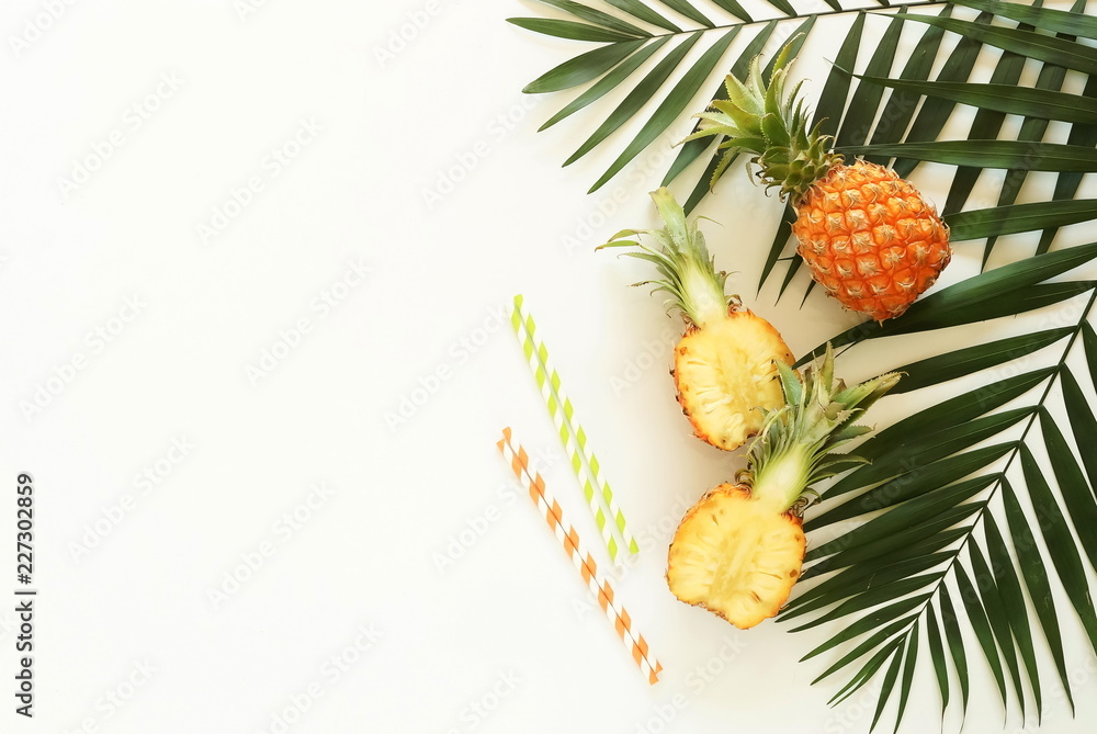 Fruits top view background. tropical green palm leaves branches and fruits pineapples top view on a white background. food concept.copy space Fruits top view background. tropical green palm leaves branches and fruits pineapples top view on a white background. food concept.copy space