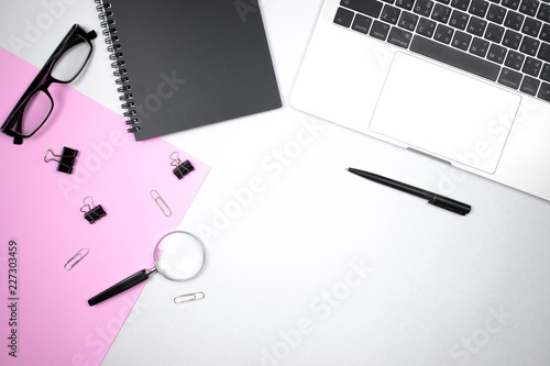 White desk top view with pink paper and accessories office.