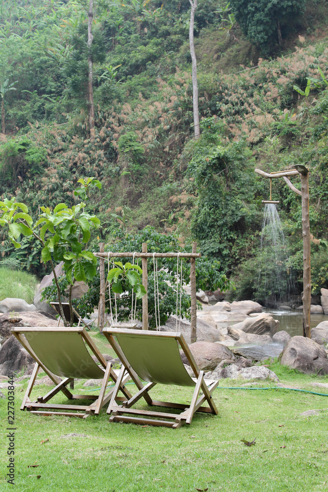 Wooden deckchair on green grass.